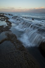 Capturing the serene beauty of a sunset on the rocky shores of Tarifa in Cadiz, where gentle waves