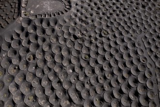 Aerial view of black volcanic soil gridded with circular sunken pits used for grape cultivation,