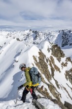 Mountaineer on the summit of Piz Grialetsch in winter, view of mountain panorama with snow, Grisons