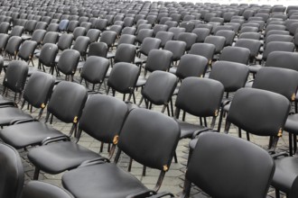 Chairs covered with gray plastic stand in rows in a function room, empty, vacant, seating