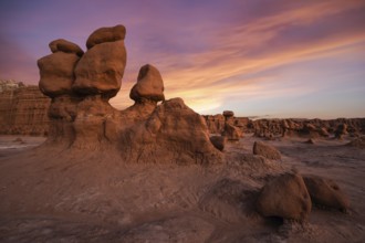 Dramatic sandstone formations under a vibrant sunset sky at Goblin Valley State Park, Utah.