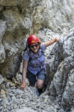 Female mountaineer with helmet climbing a rock face, ascent to the Ackerlspitze, Wilder Kaiser,