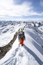 Mountaineer on a narrow mountain ridge in winter, summit of Piz Grialetsch, view of mountain