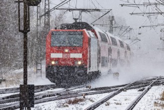 RegionalExpress RE on the road through a winter landscape in snowfall. A train on the line in the