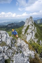 Climber on a climbing tour, on a mountain ridge, behind the summit of the Kampenwand with summit