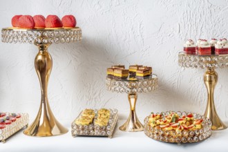 Elegant dessert assortment displayed on luxurious gold and crystal stands. Delicate pastries,