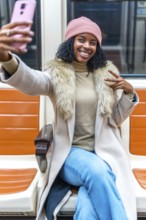 Cheerful young woman takes a selfie on public transport, making peace sign with fingers while