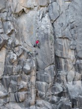 Two climbers scale a rugged cliff with traditional gear, highlighting the thrill and skill of rock