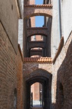 A narrow, arched passageway made of bricks with historical flair, 13th century church path, Elblag,