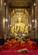 Buddhist monks praying at Wat Xieng Thong Sim ordination hall, Luang Prabang, Laos