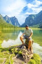 Tourist enjoying the breathtaking view of lake dobbiaco and the dolomites on a sunny summer day