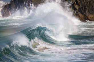 Waves crash against rocks at the mainland's easternmost point, creating rainbows in the ocean spray
