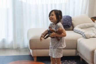 A young girl joyfully embraces her doll in a cozy living room, symbolizing love and innocence. The