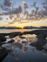 Clouds reflected in a small pond on a rocky coast, coastal landscape at sunset, Henningsvær,