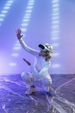 An elderly Asian woman wearing a VR headset interacts with a dynamic virtual environment,