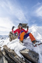 Happy mountaineer with ice axes and crampons on the summit of Piz Grialetsch in winter, Graubünden