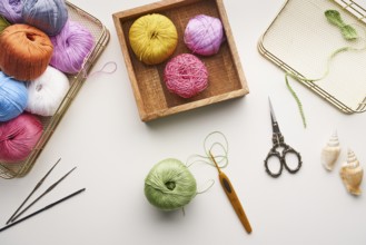 Top view of various colored yarns, crochet hooks, and ornate scissors arranged for needlework and