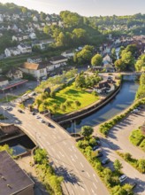 Aerial view of a bridge over a canal in a town with green spaces and many trees in daylight, Calw,