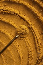A vibrant close-up of golden curry powder, showcasing its textured surface with swirling patterns