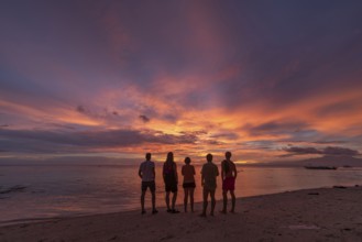 Back view silhouette of unrecognizable friends standing on a beach in the Philippines, watching a