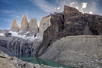 Massive rock formations and snow surround a narrow mountain lake, The rock towers of Torres del