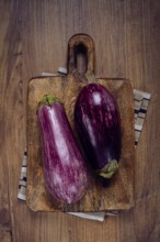 Purple and white eggplant, on a wooden chopping board, top view, raw eggplant, no people