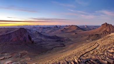 Vast desert landscape at sunset with mountain ranges on the horizon, The landscape of the Ahaggar