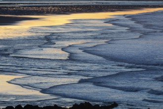 Low tide and gentle waves, at dusk on the North Sea, on the North-east coast of Northumberland,