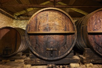 Large wooden barrel with engravings surrounded by stone walls in a wine cellar, Achaia Clauss