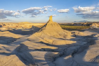 A panoramic view of dramatically eroded sandstone formations under the warm light of a setting sun