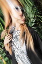 A stylish woman in sunglasses captured with motion blur effect, creating a dynamic and artistic