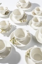 Top view of a tasteful arrangement of white coffee cups and saucers, adorned with delicate spring