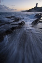 A mesmerizing sunset over the coast of Cadiz in Tarifa. Waves crash onto rocky shores as the sky