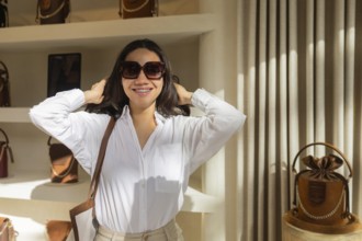 A smiling customer in a white shirt and sunglasses explores a chic bag store. Display shelves