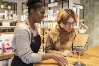 A employee in a cosmetics store help a customer with makeup. She is focused on providing excellent