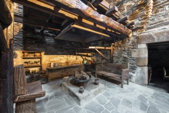 Traditional rustic kitchen inside a country house in Lugo, Spain, featuring stone walls, wooden