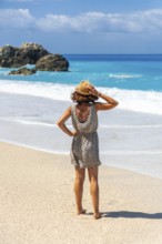 A woman walking on the turquoise water Megali Petra beach of Lefkada island, Ionian Sea, Greece