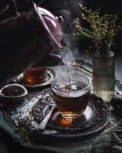 A warm cup of hot tea infused with anise is elegantly placed on an ornate tray. Steam wafts gently,