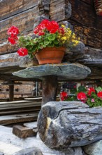 Flower-decorated barn on wooden supports and stone slabs, historic village centre, Grimentz, Val