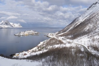 Serene winter view of Husoy, Norway, with a snow-covered coastline, calm sea, and dramatic