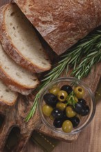 Sliced ciabatta, on a chopping board, with rosemary and olives, Italian bread, close-up, Italian