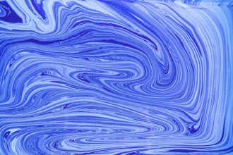 This image showcases a pattern of blue and white acrylic paint swirls resembling marble. The fluid,