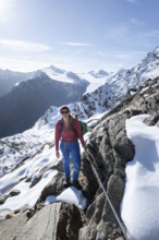 Mountaineer on a secured path with snow, climbing up to Ramoljoch, behind mountain Ramolkogel,