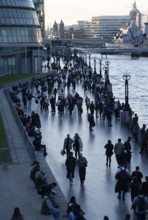 People walking next to the River Thames as evening falls, The Queen's Walk, Southwark, London,
