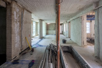 Unfinished building interior showcases raw concrete walls, scattered tools, and construction
