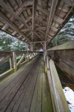 Interior view of a wooden bridge over a snow-covered forest path, Kälberbrücke, Enzklösterle, Calw