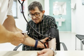A healthcare professional checks the blood pressure of a resident in a mental health facility,