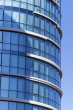 Modern architecture, highlighting a curved building with a vibrant blue glass facade against a