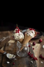 Two ice cream cones filled with creamy dessert, garnished with fresh currants, artistically placed