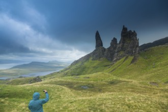 UK. Scotland. Isle of Skye. A tourist taking a picture of the Old Man of Storr during a storm